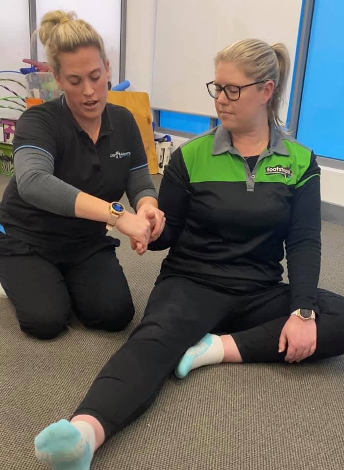 A Little Achievers occupational therapist guiding an adult client through a hand and wrist stretch
